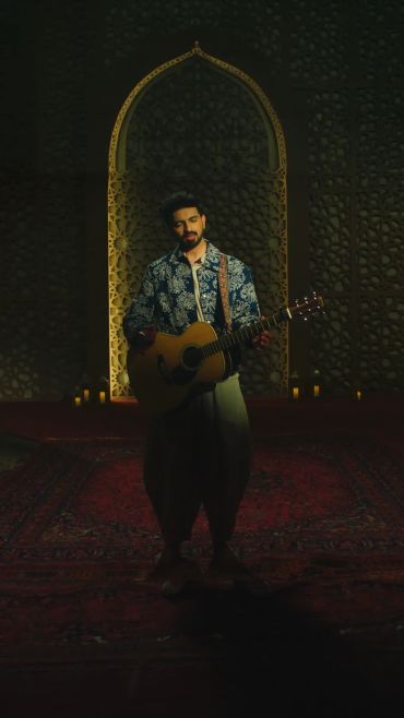 Man playing guitar in a dimly lit ornate room.