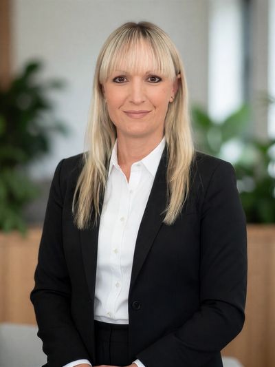 Professional woman in black suit with blonde hair smiling.