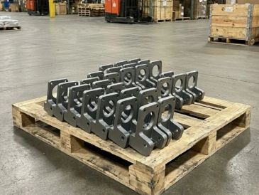 Metal brackets neatly arranged on a wooden pallet in a warehouse.