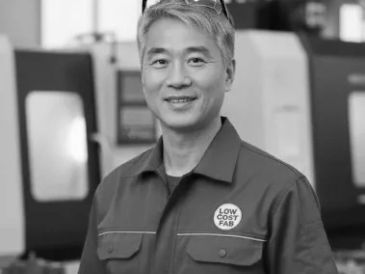 Smiling man in workwear with safety glasses on head in a workshop.