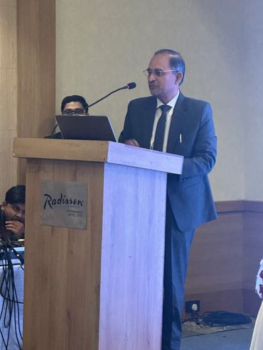Man in suit giving a speech at a Radisson hotel podium.