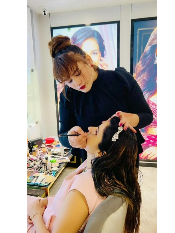Makeup artist applying makeup on a woman in a beauty salon.
