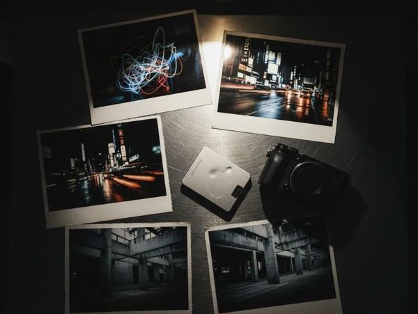 Polaroid photos and cameras arranged on a dark surface.