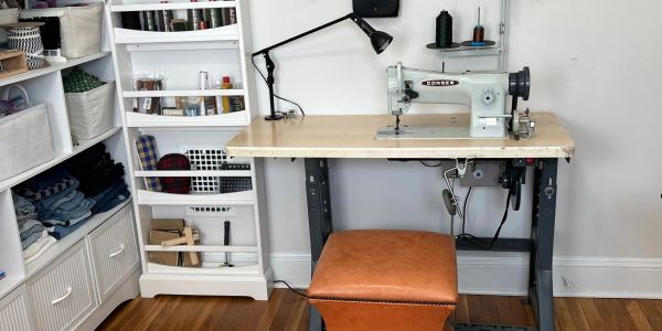 Sewing machine setup with shelves and a stool.