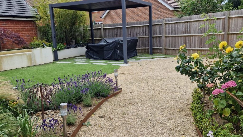 Image of a garden, with roses, lavender and a pergoda seating area.