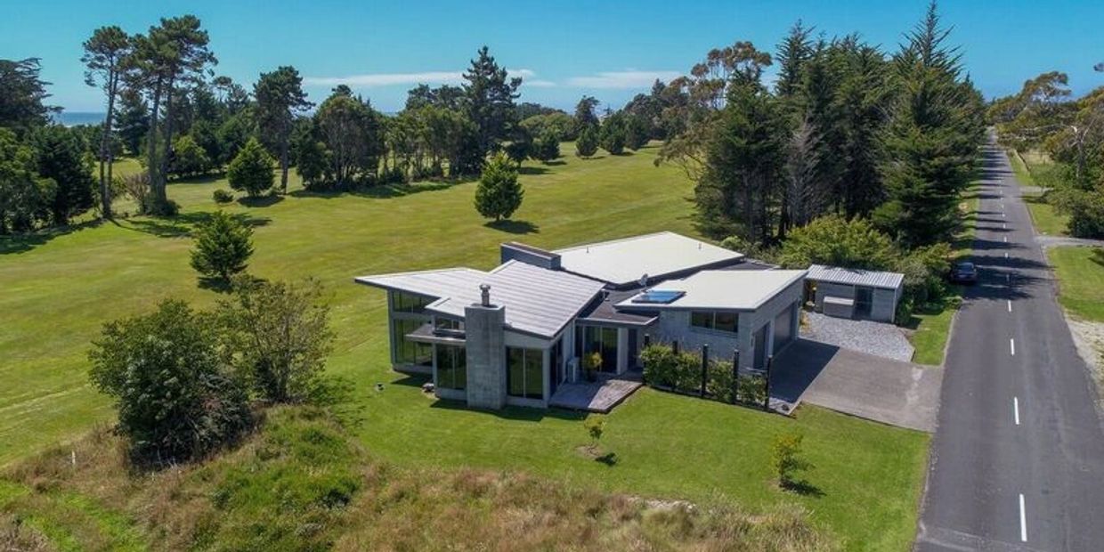 Modern house surrounded by green fields and trees.