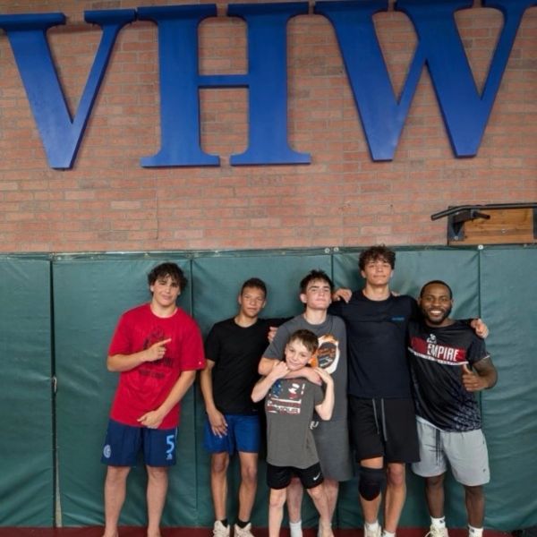 Group of six people posing happily inside a gym.