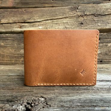 Simple brown leather wallet on rustic wooden surface.
