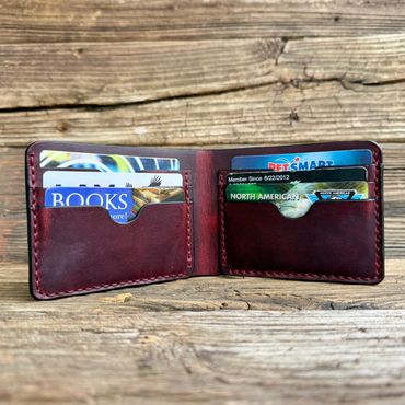 Open leather wallet displaying several cards on a rustic wooden surface.