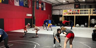 Kids practicing wrestling in a gym.