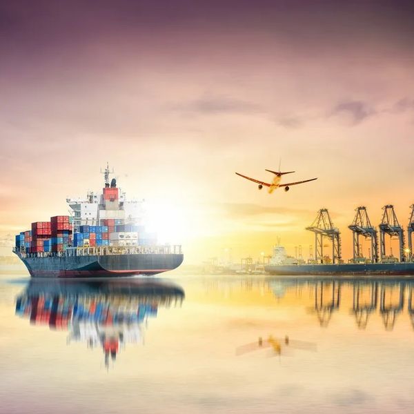 Cargo ship and airplane at sunrise near port cranes.