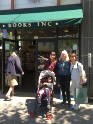 three women and a child in a stroller outside a bookstore