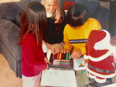 a woman and two children looking at coloring pens