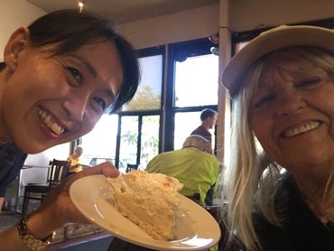 a person holding a plate with a dessert next to a person wearing a hat