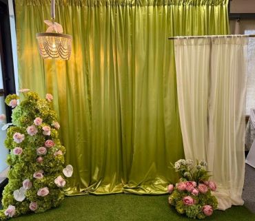 Decorative green and white drapery with floral arrangements.
