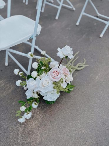 White floral arrangement by a white chair on a concrete surface.