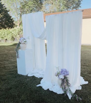 Elegant white draped fabric decoration with flowers outdoors.