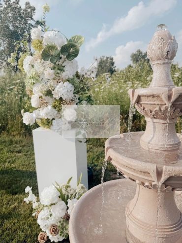 Outdoor fountain and white floral arrangements.