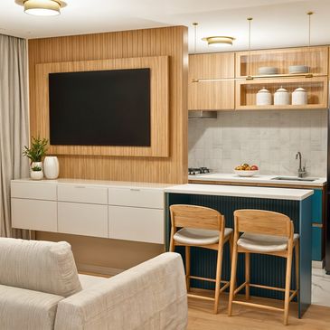Sala de estar conjugada com cozinha de apartamento. Móveis em tom de madeira, branco e azul vivo.