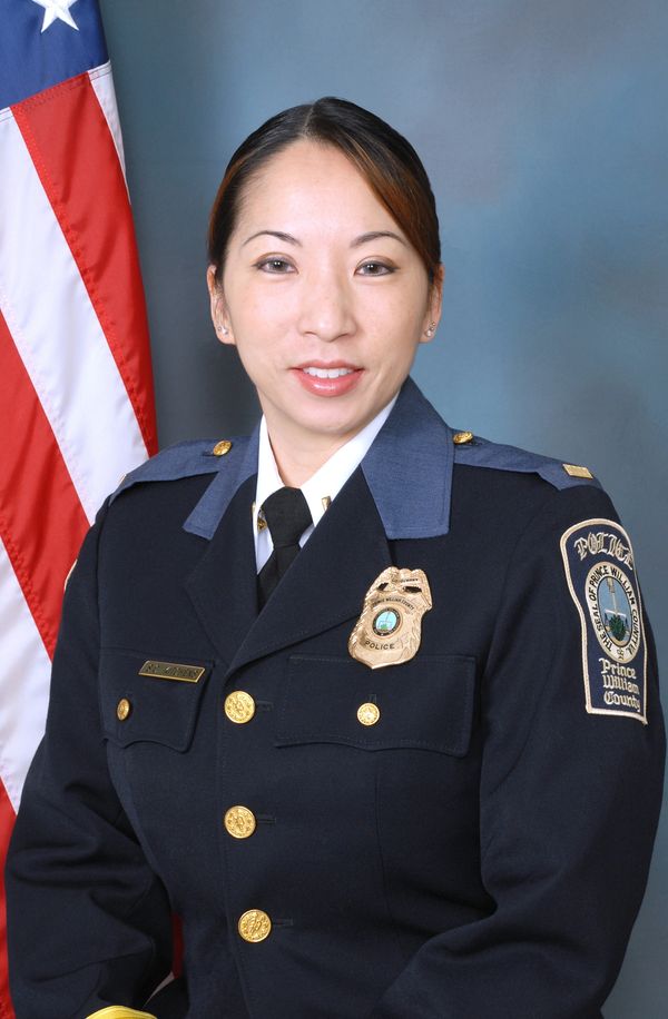 Female police officer in uniform posing in front of an American flag.