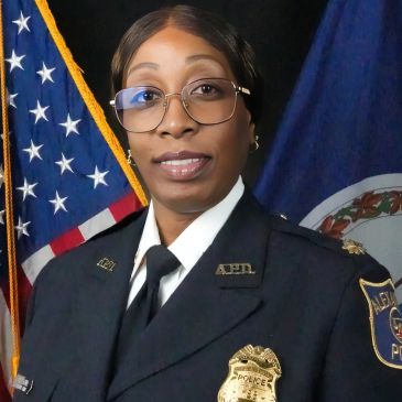 Policewoman in uniform posing with flags.