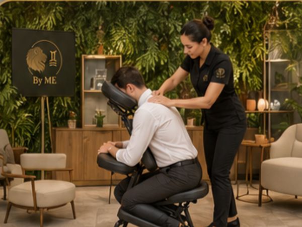 A man receiving a seated massage in a cozy, green-themed room.