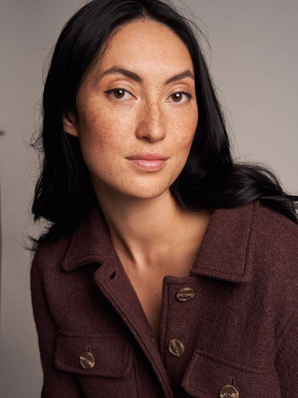 Woman with freckles wearing a brown jacket.