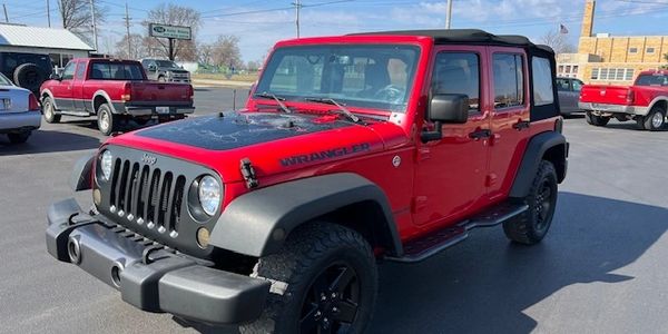 Red Jeep Wrangler parked outdoors on a sunny day.