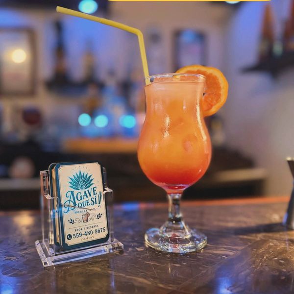 Colorful Sex on the Beach cocktail with orange garnish on bar counter.