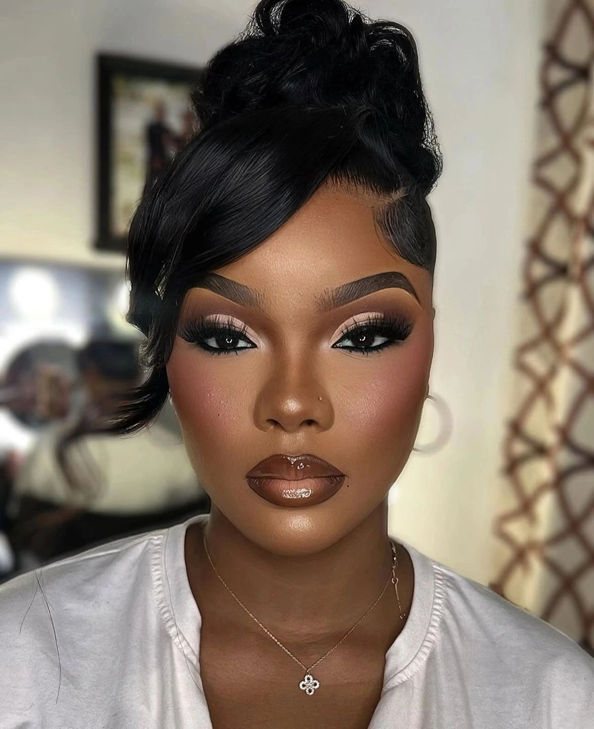 Close-up portrait of a woman with glamorous makeup and a stylish updo hairstyle.