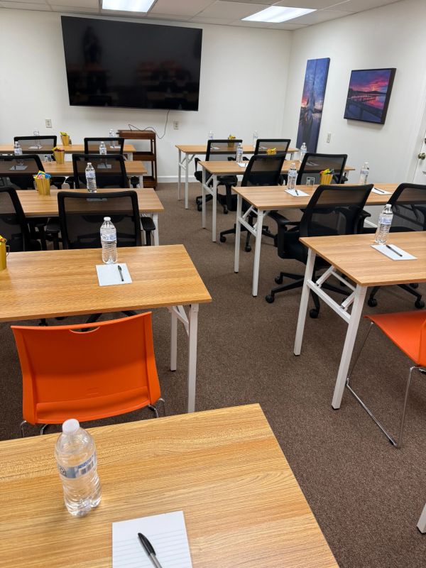 Classroom setup with desks, chairs, water bottles, and a TV screen.