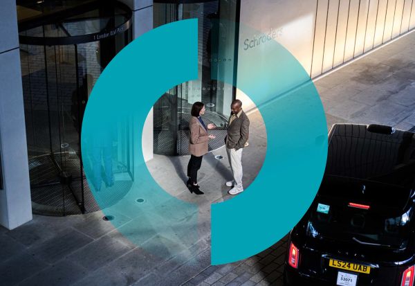 Two people conversing beside a building entrance and a black car.