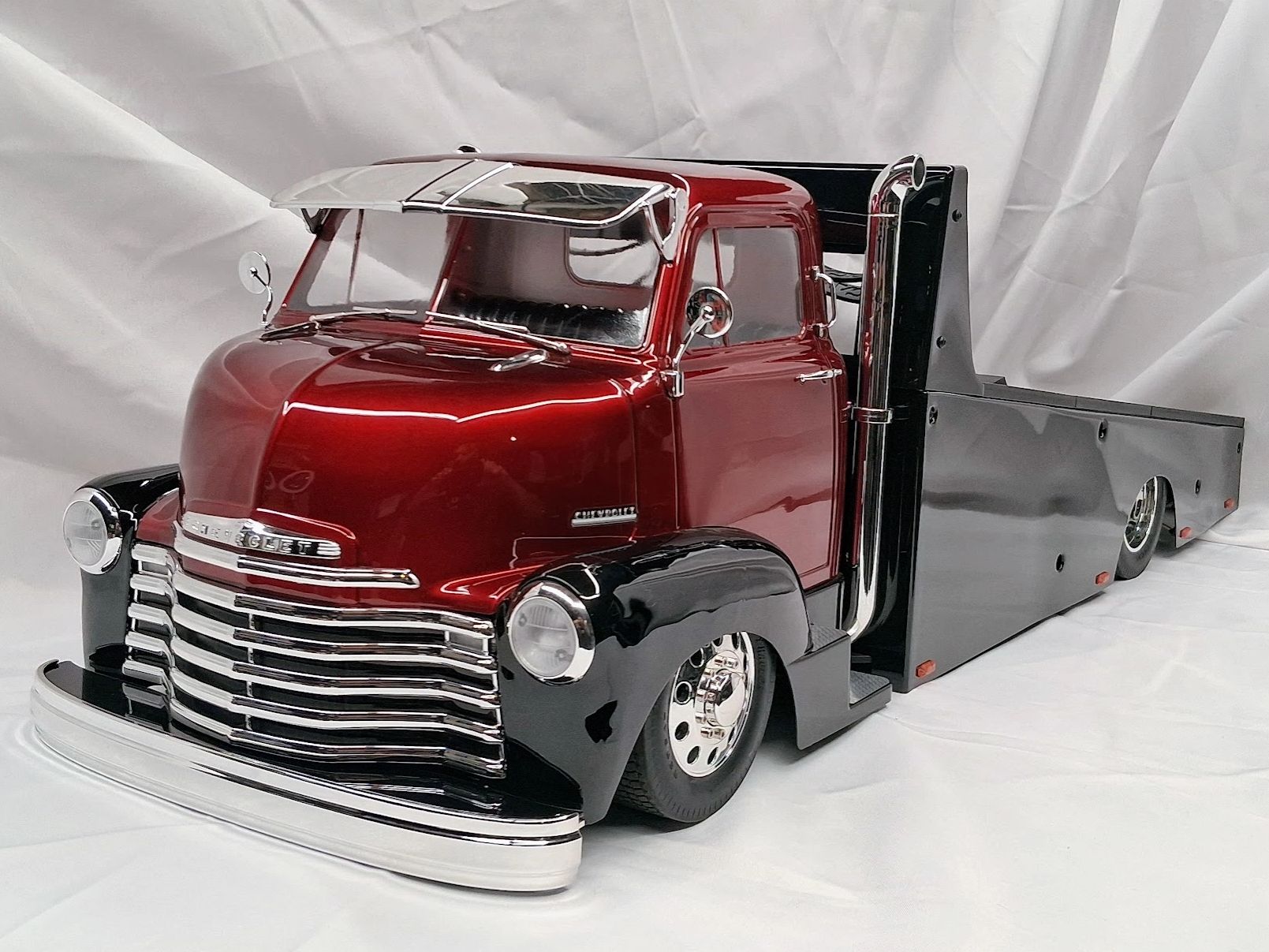 Custom vintage Chevrolet flatbed truck with a shiny red and black finish.