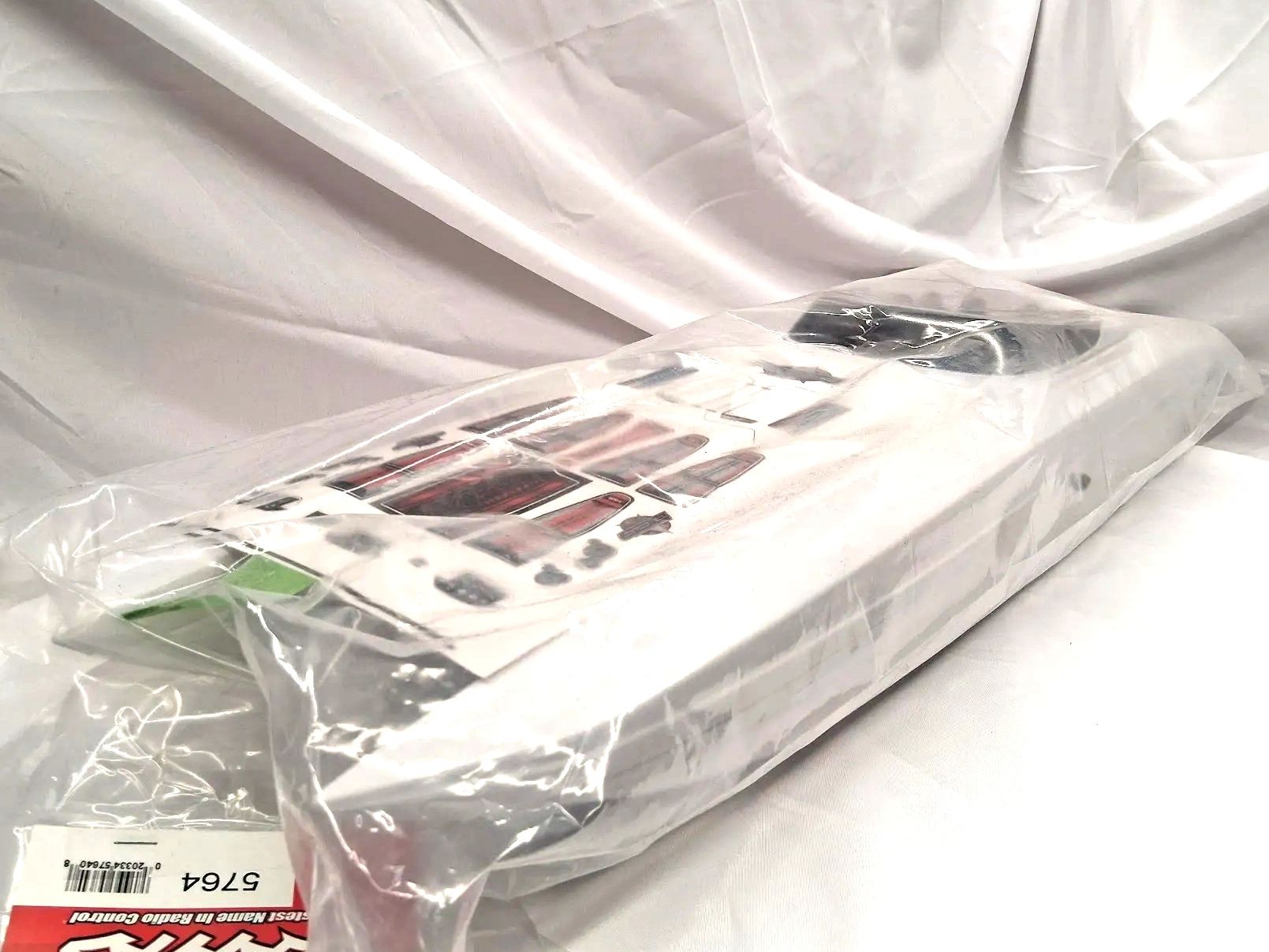 A white RC car body shell in a plastic bag with decals on top.
