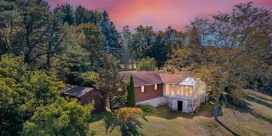A cozy house surrounded by trees at sunset.