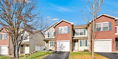 Suburban row of modern townhouses with garages and leafless trees.