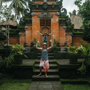 Two men posing happily in front of a traditional Balinese temple.