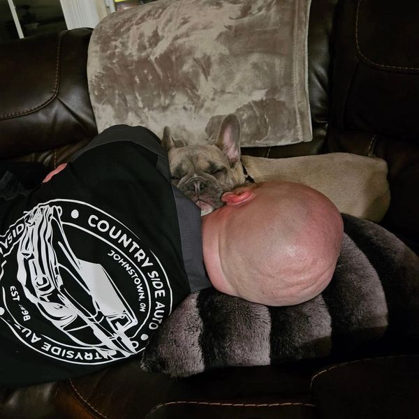 A man and his dog napping closely together on a couch.