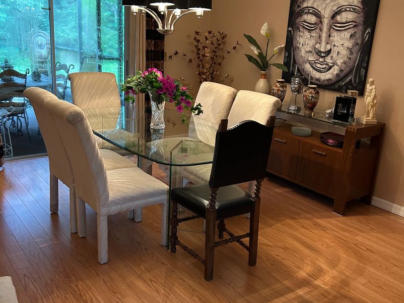 Elegant dining room with glass table and flower centerpiece.