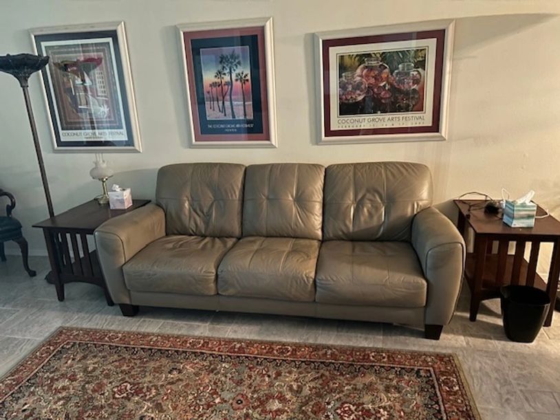Leather sofa between two wooden side tables with framed art above.