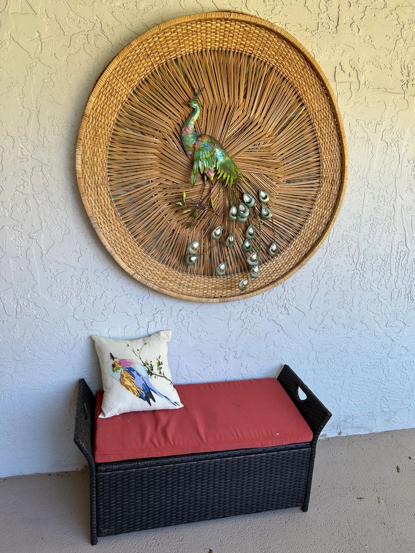 Decorative peacock wall art above a cushioned bench with a bird pillow.