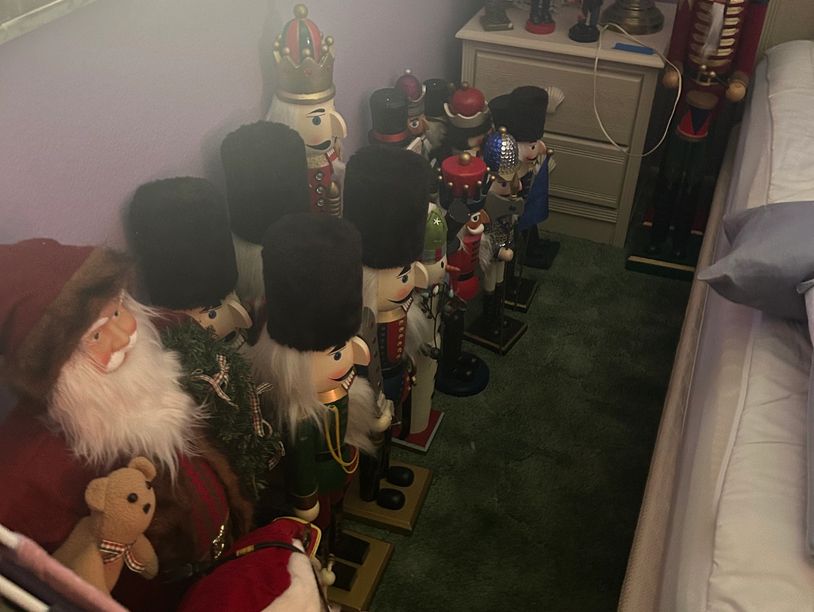 Row of nutcracker dolls lined up beside a bed.