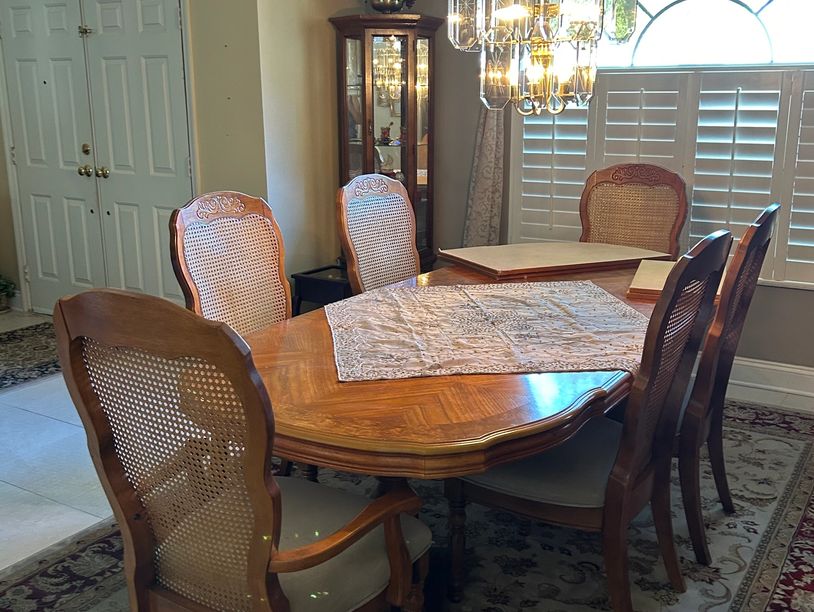Wooden dining table with six chairs in a bright room.