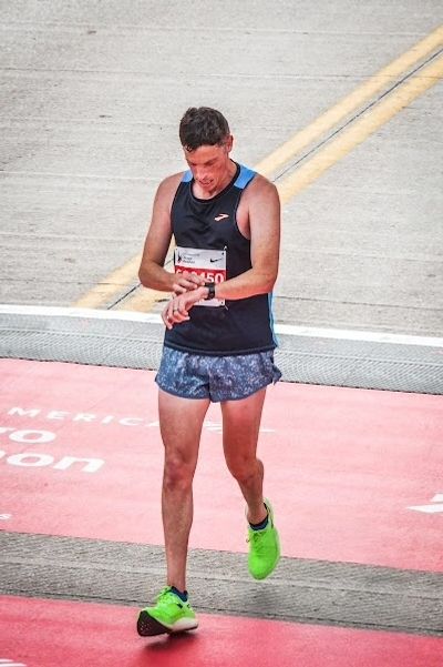 Runner checking his watch after crossing the finish line.