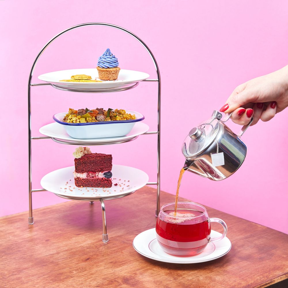 Tea being poured with a three-tiered tray of assorted desserts and Gourmet dog bowl.