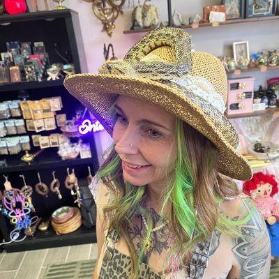 Woman with green hair wearing a straw hat in a shop.