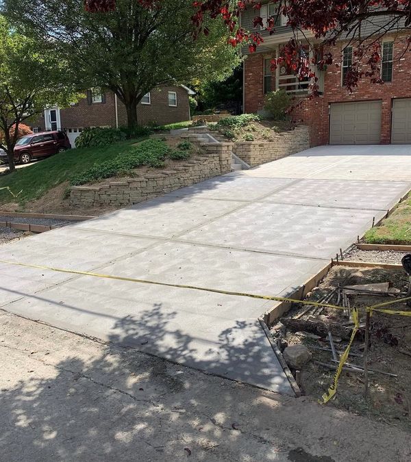 Newly poured concrete driveway leading to a brick house with garage.