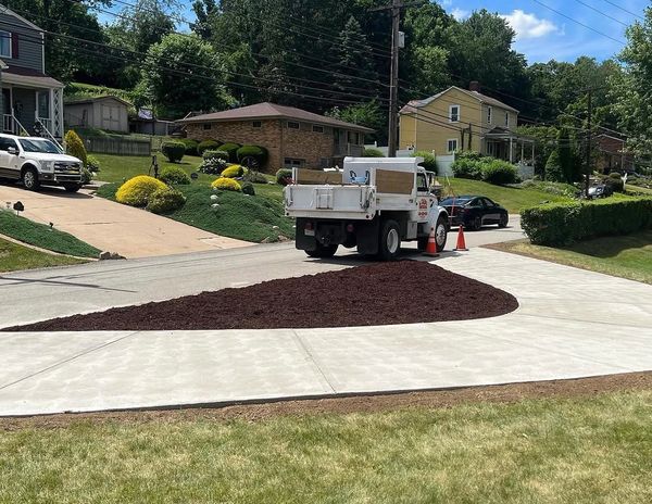 Fresh mulch spread in a newly paved driveway with a work truck nearby.