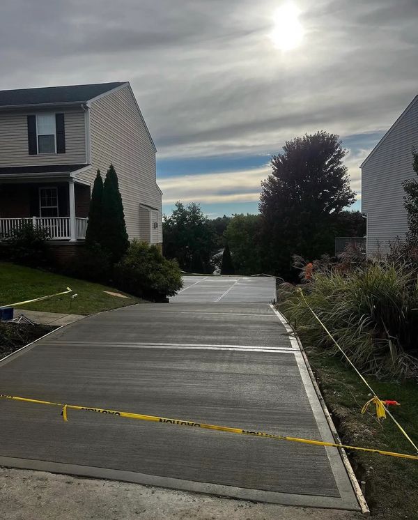 Newly poured concrete driveway drying under the sun beside suburban houses.