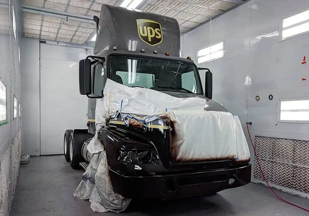 UPS truck undergoing partial paintwork in a workshop.